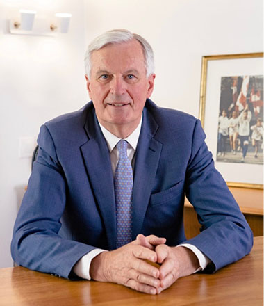 Michel Barnier siiting at a desk in a suit