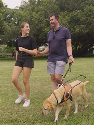 Hailey and friend Henry walking in a park with his guide dog, Yas. 