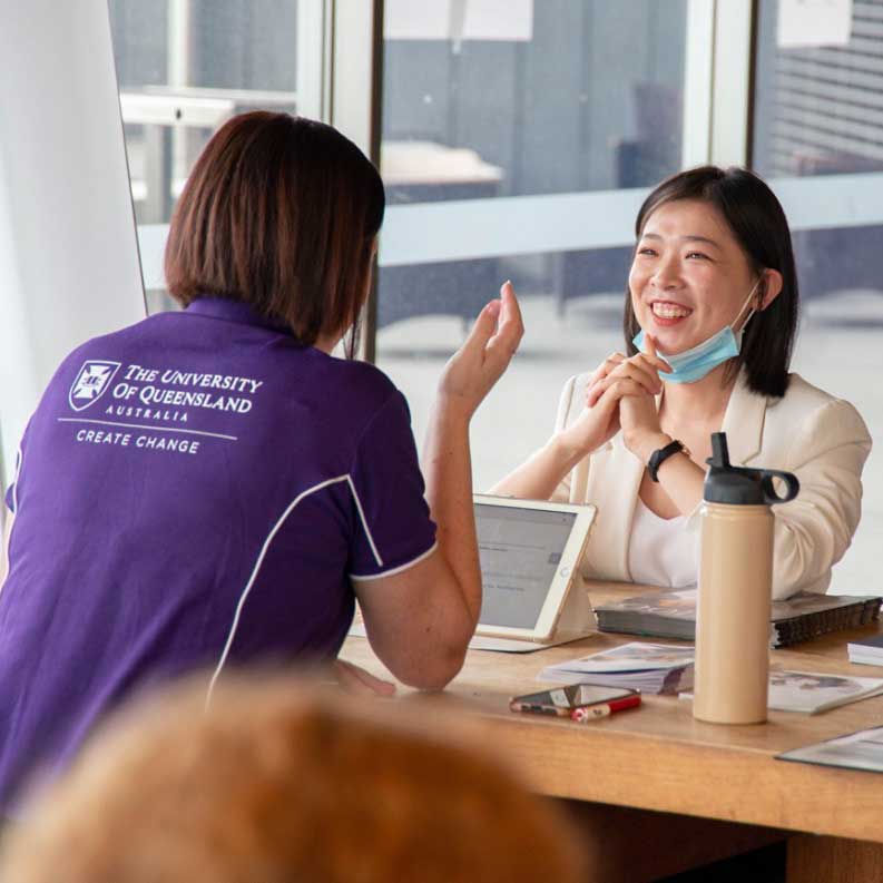 Student talking with a UQ staff member in purple shirt 