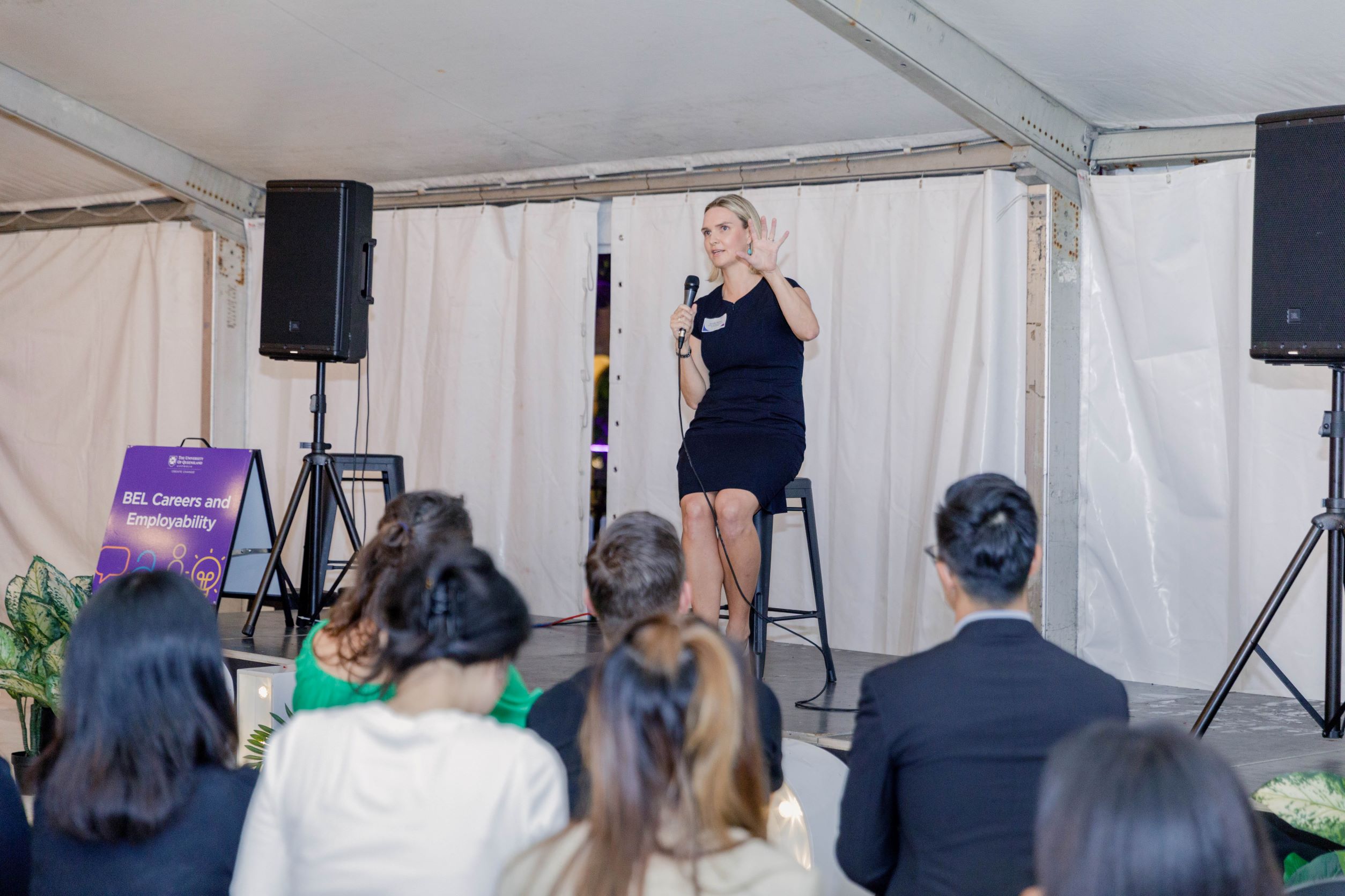 Jennifer Nielsen seated on a stool talking to an audience seated in front of her