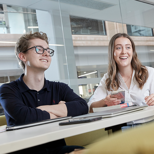 two BEL students smiling at work desk 