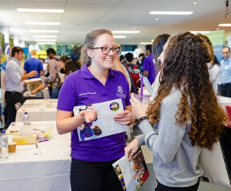 BEL student wearing a purple shirt chatting in an ambassadorial role.