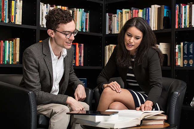 business man and women in library looking at book