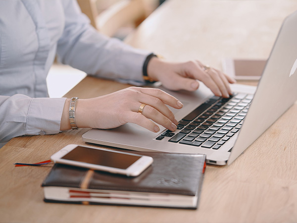 a woman's hands typing on a laptop 