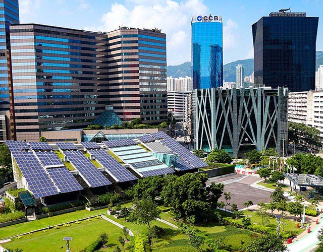 modern cityscape with lots of green area and a building covered in solar panels. 