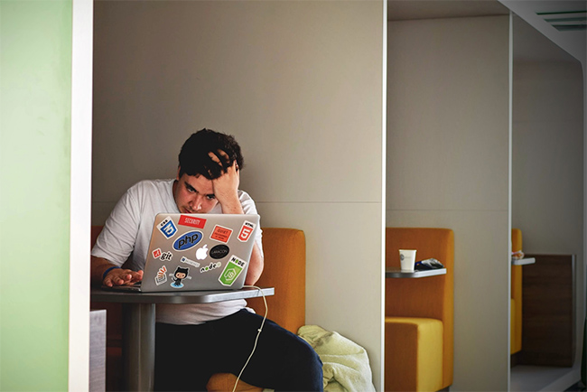 stressed out student working on a laptop.