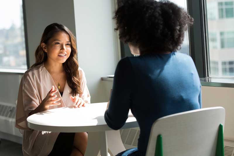 Young woman at table being interviewed