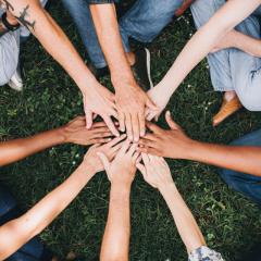This is an image of a group of people touching hands in a circle