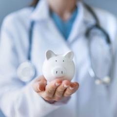 This is an image of a person dressed as a doctor holding a piggy bank