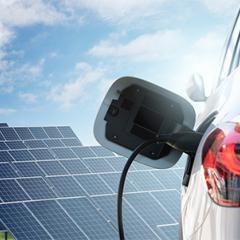 photoshop image of a plugged in electric car in front of solar panels