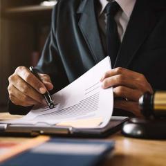 Corporate figure looking over a contract with a pen 